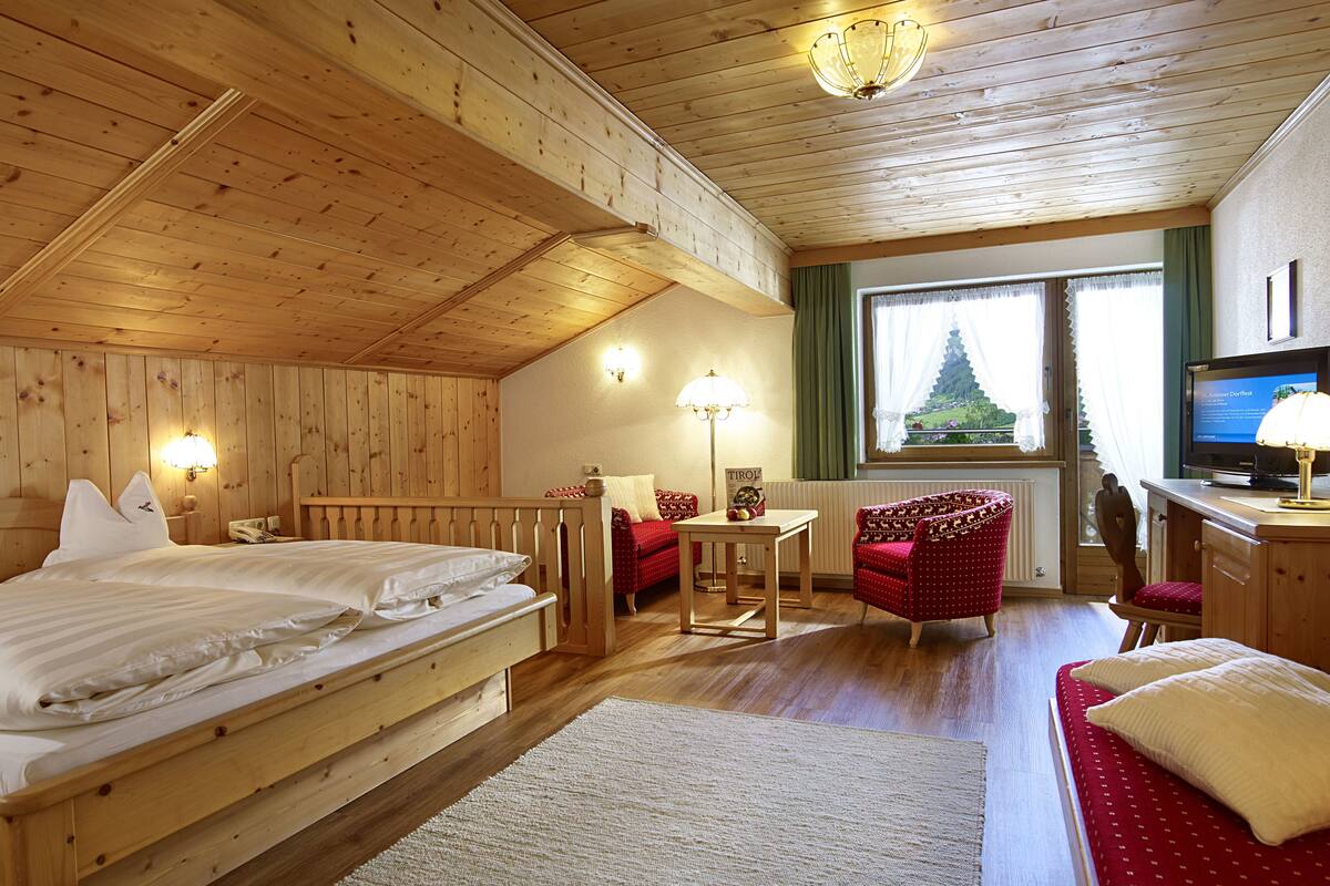 A wooden room with a bed, a desk, a chair, and a television.