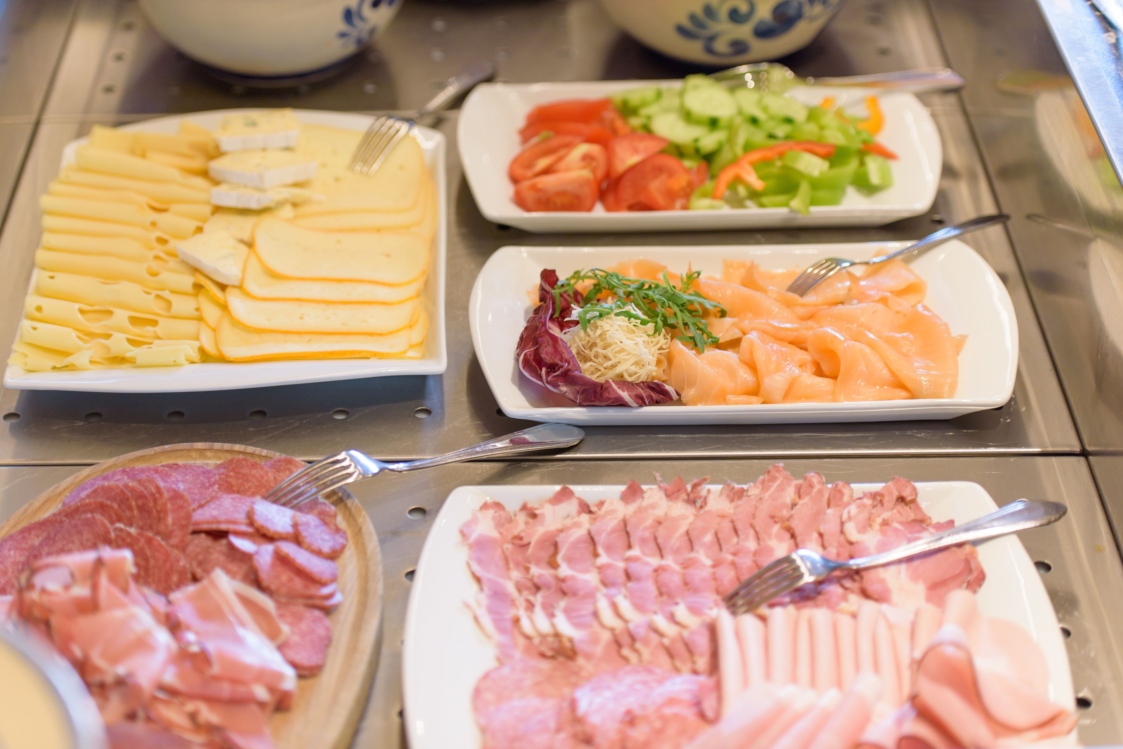 A buffet with various food items including sliced meats, cheeses, and vegetables.