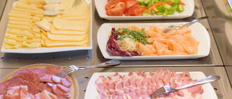A buffet with various food items including sliced meats, cheeses, and vegetables.