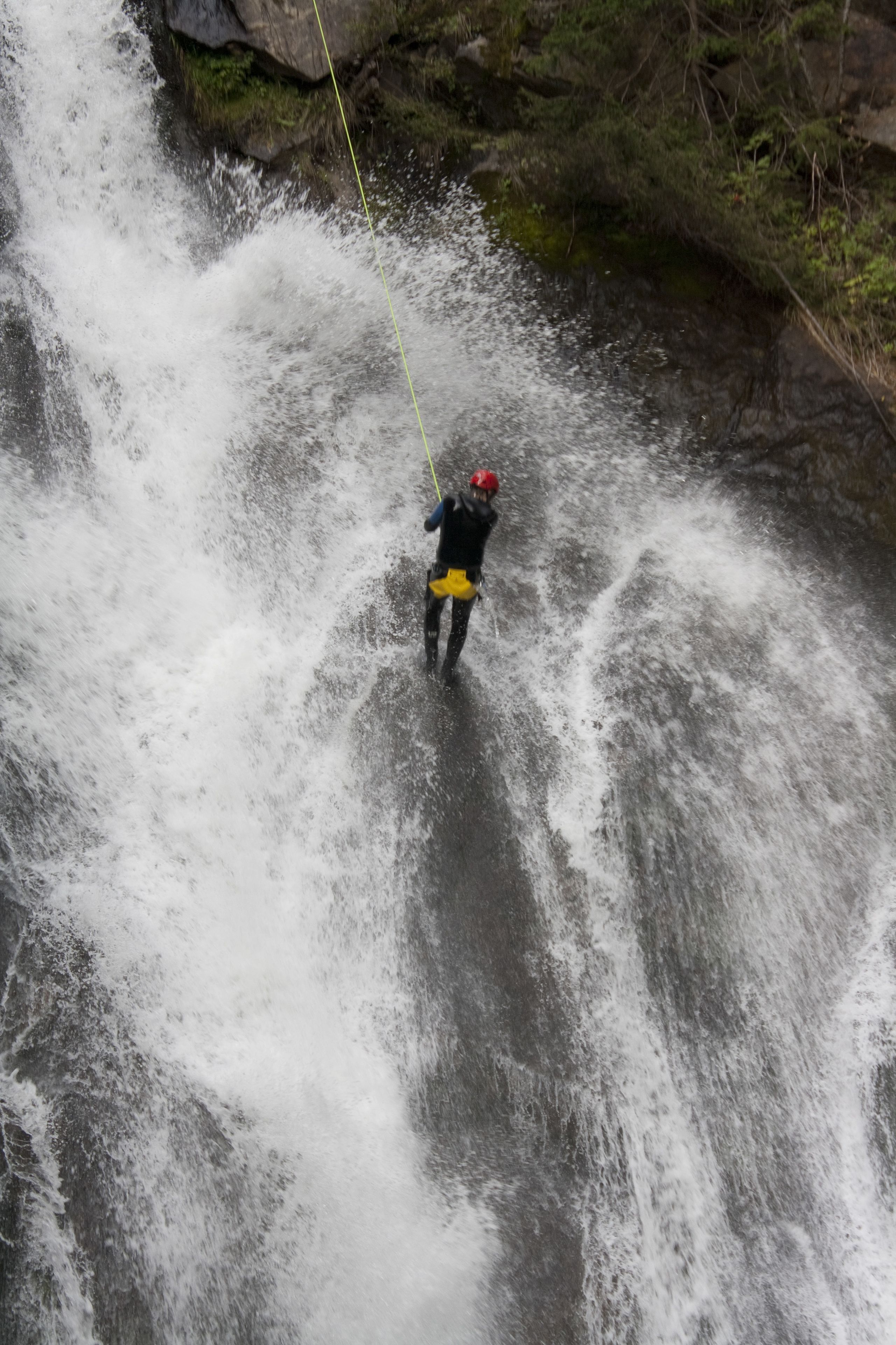 Una persona descendiendo en rappel por una cascada.