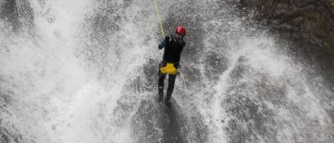 Una persona descendiendo en rappel por una cascada.