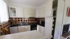 Una cucina con mobili bianchi, un piano di lavoro in marmo, una lavastoviglie e un fornello.