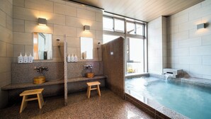 Ein modernes Badezimmer mit Granitwaschtischen, zwei Waschbecken, Holzschemeln und einer großen Badewanne.