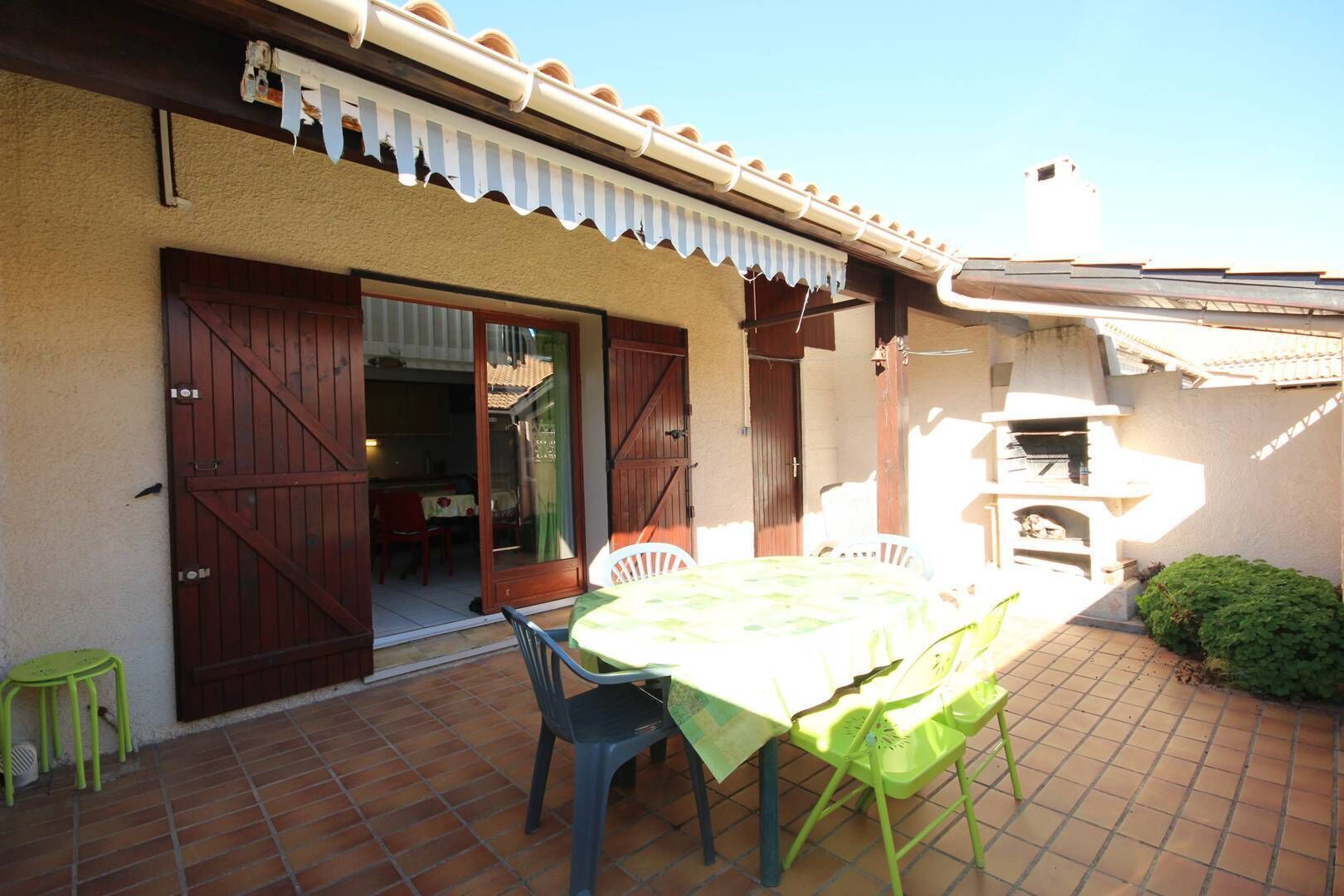 Un pati amb taula i cadires, una barbacoa i una porta corredissa que dona a l'interior.