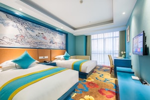 A hotel room with two beds, a desk, a chair, a TV, and a large wall mural.