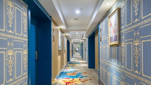 Un largo pasillo con paredes azules y una alfombra estampada.