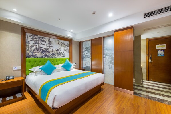 A hotel room with a large bed, a green headboard, and a mural on the wall.
