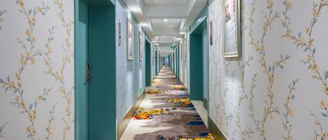 A long hallway with floral wallpaper and a colorful carpet.