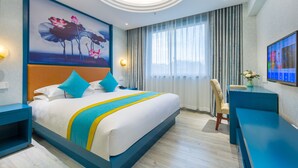 Una habitación de hotel moderna con una cama grande, un escritorio y un televisor montado en la pared.