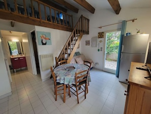 A cozy kitchen with a dining area, wooden staircase, and a view of the outdoors. - Villa for 4 persons, with nice fenced corner terrace, only 400m vom the beach of Portiragnes plage (PORTIRAGNES)