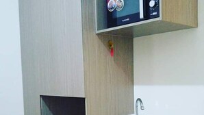 A modern kitchen with a built-in microwave, a stainless steel sink, and a coffee maker on a shelf.