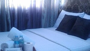 A neatly made bed with pillows, a tray with toiletries, and a sign indicating a personal guest list.