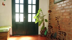 A room with a green door, a wooden chest, a giraffe sculpture, and a potted plant. - Hospederia Marques Casa Ramos (Villa de Leyva)