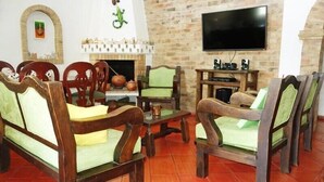 A cozy living room with wooden furniture, a fireplace, and a flat-screen TV. - Hospederia Marques Casa Ramos (Villa de Leyva)
