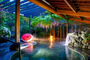 A hot spring area with a wooden pergola, a red umbrella, and a waterfall. - Ooedo Onsen Monogatari Shinshu Kakeyu (Ueda)
