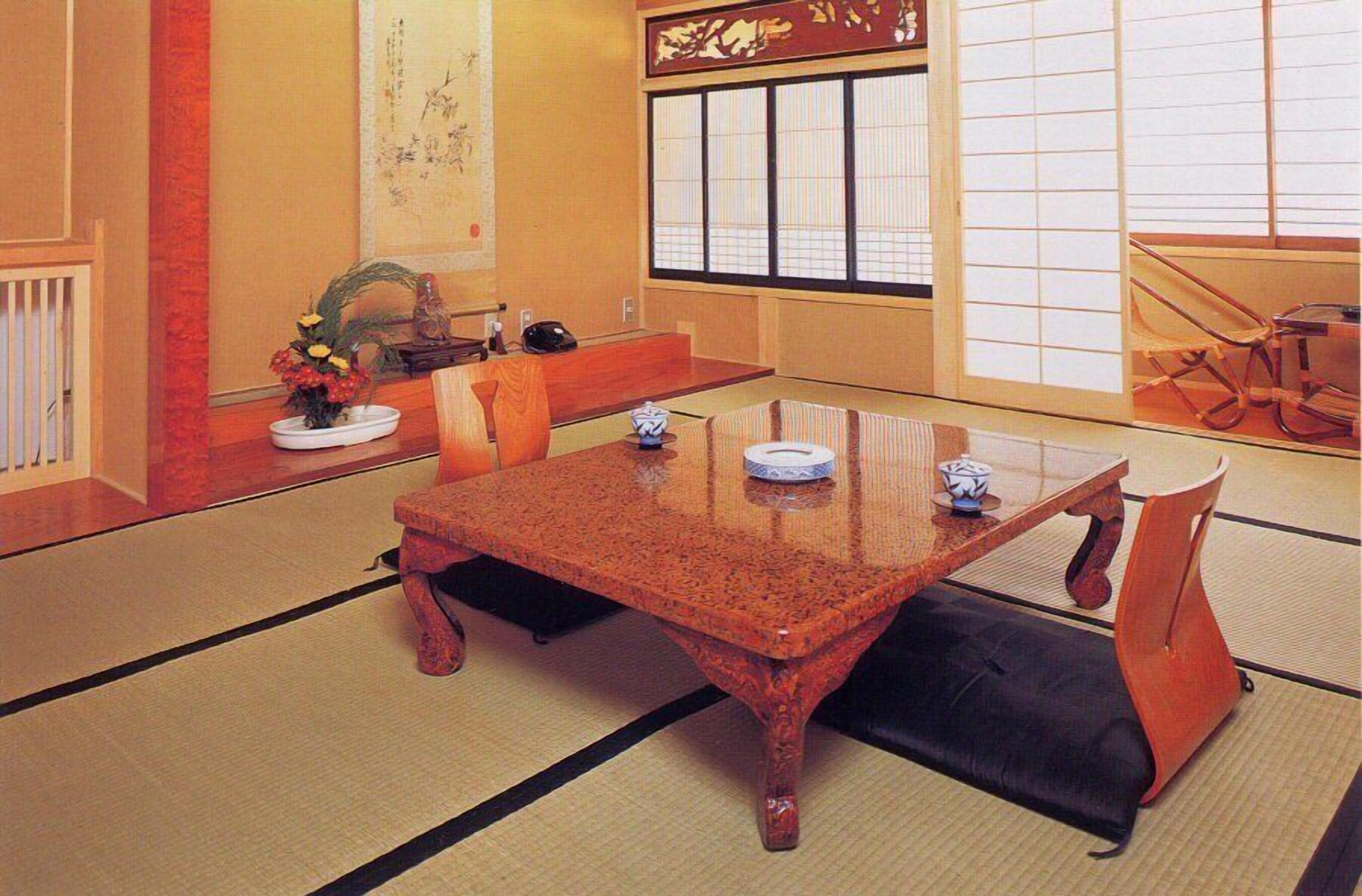A traditional Japanese-style room with tatami flooring, a low wooden table, and a sliding door with a decorative screen.