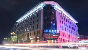 Ein mehrstöckiges Hotel mit einer geschwungenen Fassade, beleuchteter Beschilderung und einem markanten Eingang.