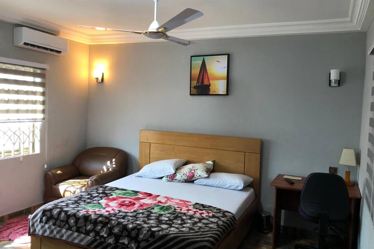 Ein Schlafzimmer mit einem Bett, einem Sessel, einem Schreibtisch und einem Deckenventilator.