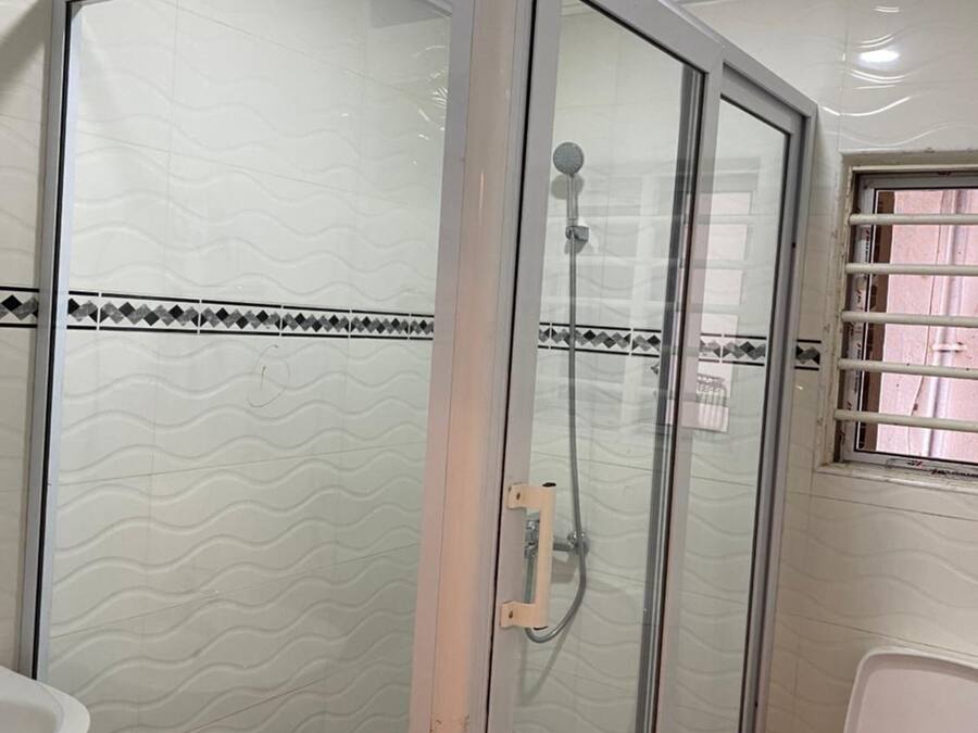 A bathroom with a glass-enclosed shower, a toilet, and a sink.