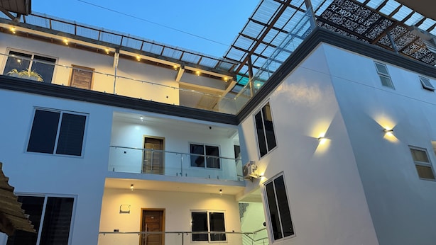 Un edificio de varios pisos con balcones, ventanas amplias y una estructura de techo de cristal.