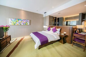 A modern hotel room with a large bed, a bedside table with a phone, a mirror, and a small desk with a chair. - Yunman Hotel Kunming Donghua (Kunming)