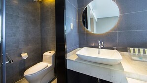 Uma casa de banho moderna com sanita, lavatório e espelho.