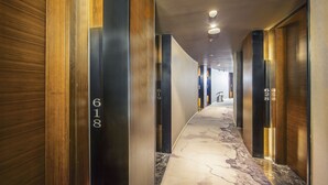 A modern hotel hallway with wood paneling and numbered doors, leading to rooms. - Yunman Hotel Kunming Donghua (Kunming)