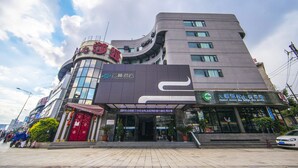 A modern hotel with a curved facade, large windows, and a prominent entrance with a red door. - Yunman Hotel Kunming Donghua (Kunming)