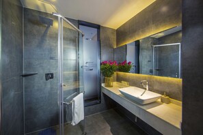 A modern bathroom with a glass shower enclosure, a white sink, and a large mirror. - Yunman Hotel Kunming Donghua (Kunming)