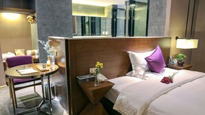 A hotel room with a bed, a desk with a chair, a small table, a nightstand, a mirror, and a wall-mounted TV. - Yunman Hotel Kunming Donghua (Kunming)