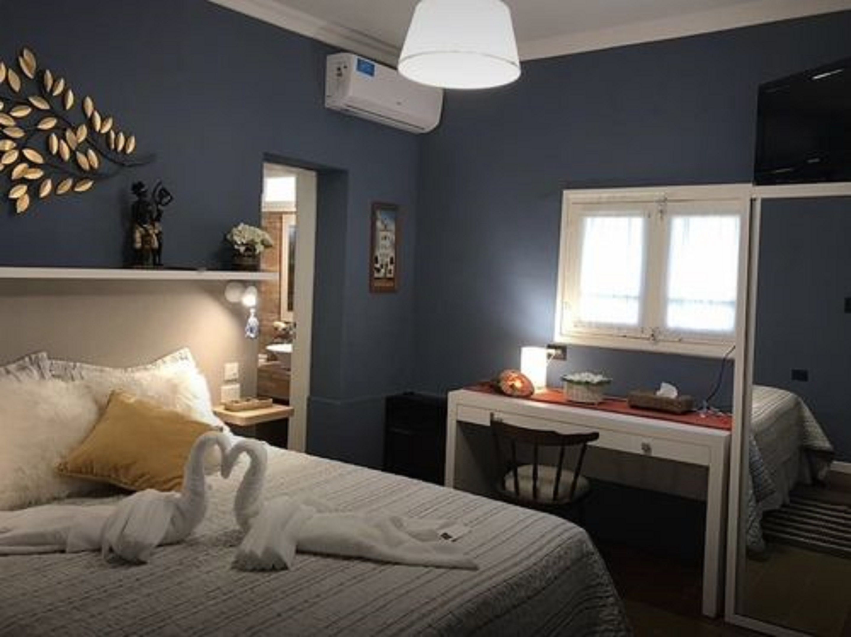 A bedroom with a bed, a desk, and a window.