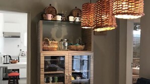 Un comedor con una mesa dispuesta para dos personas, una cesta de fruta y lámparas de mimbre.
