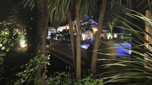Vista nocturna de un resort con palmeras y una zona de piscina.