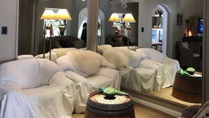 Una habitación moderna con un espejo grande, un sofá y un barril de madera.