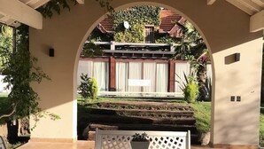 Un patio exterior con una zona de estar techada, una mesa y sillas.
