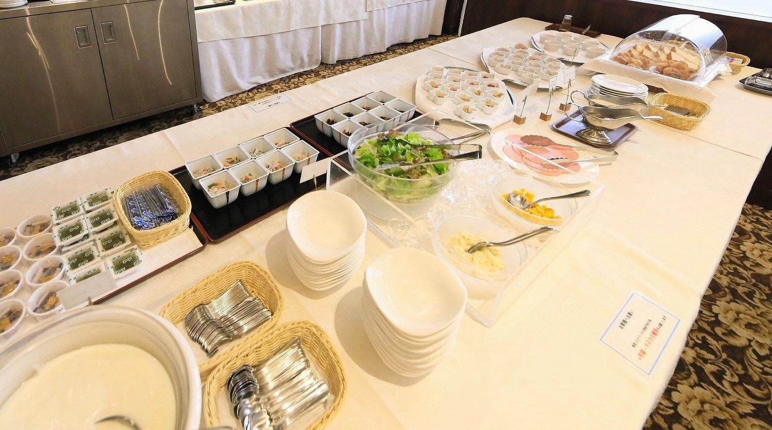 A buffet table with various food items and utensils.