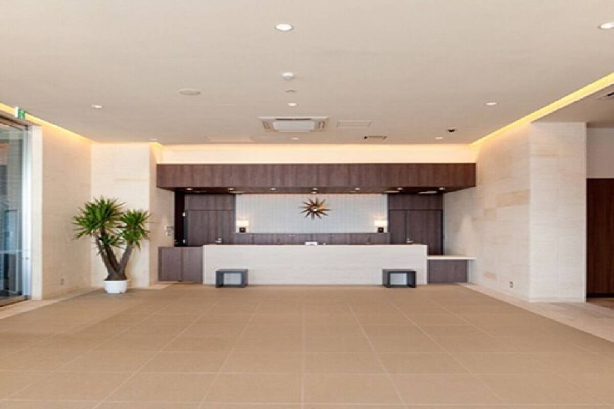 Eine großzügige Lobby mit einer Rezeption, einem dekorativen Wandbild und einem Blumentopf.