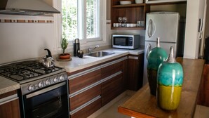 A modern kitchen with a stove, microwave, and refrigerator. There is a window with a view of trees outside.
