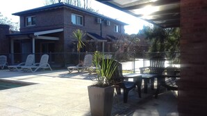 A house with a patio area featuring outdoor furniture and a swimming pool.