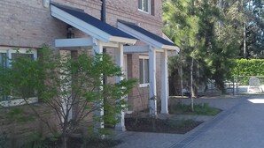 A brick building with a covered porch, a small tree, and a paved driveway.
