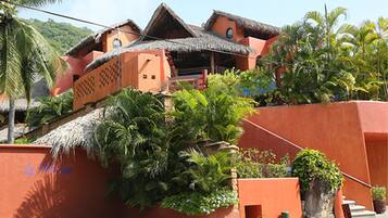 Un edificio tradicional con tejados de paja, rodeado de abundante vegetación y palmeras.