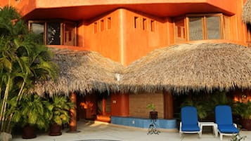 A resort with a pool, thatched-roof buildings, and lounge chairs.