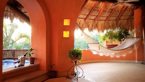A room with a thatched roof, a hammock, and a pool. - Villa Carolina Boutique Hotel (Zihuatanejo)