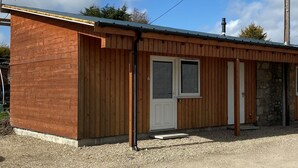 A wooden building with multiple doors and windows, likely a small lodge or cabin. - Ivy Cottage Serviced Accommodation (Aberdeen)