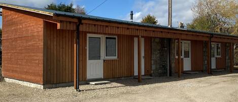 A wooden building with multiple doors and windows, likely a small lodge or cabin.