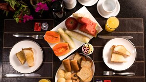 Een ontbijtsetting met borden toast, fruit en gebak op een tafel met bestek en toevoegingen.