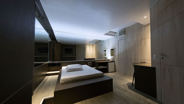 Een moderne slaapkamer met een groot bed, een bureau en een spiegel.