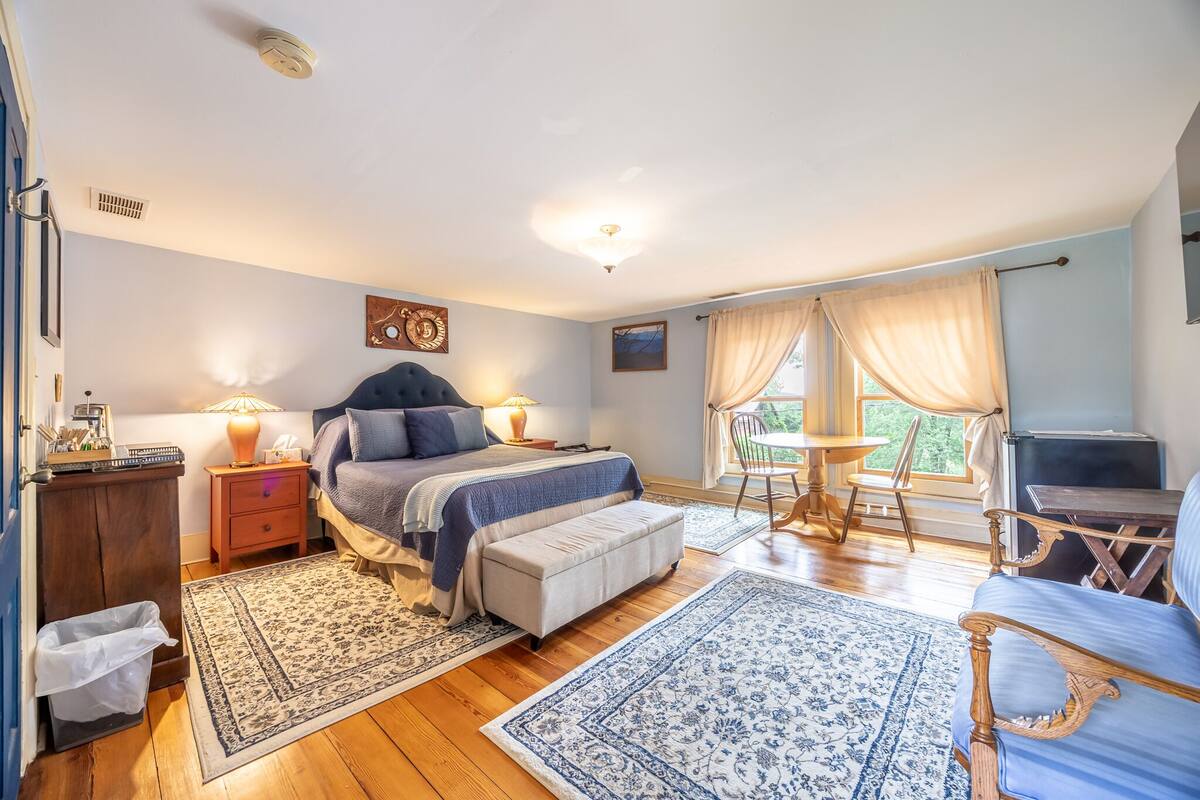 A bedroom with a bed, bedside tables, a desk, a chair, and a window with curtains.