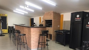 Una cucina con forno a mattoni, sgabelli da bar e frigorifero.
