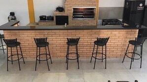 Cucina con parete rivestita in mattoni, forno integrato e quattro sgabelli da bar.